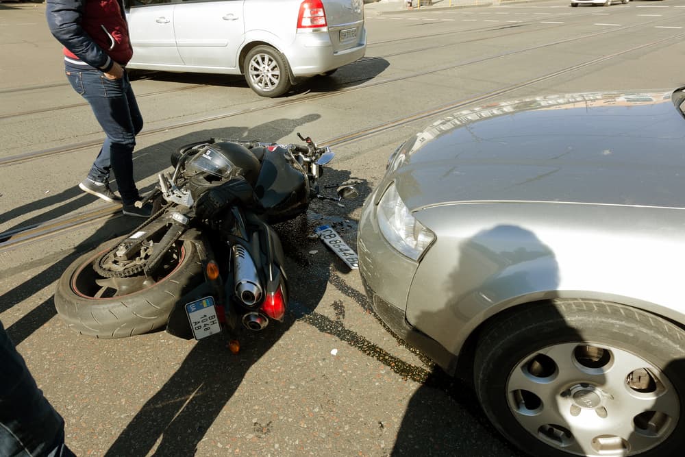 Collision between motorcycle and car on road. Motorcycle crashed into car during accident.